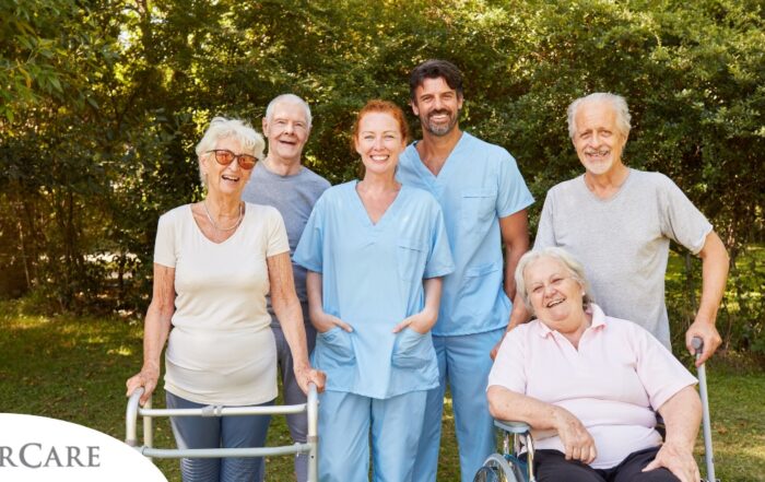 2 caregivers and seniors smile while in a group representing how caregivers can facilitate socialization.