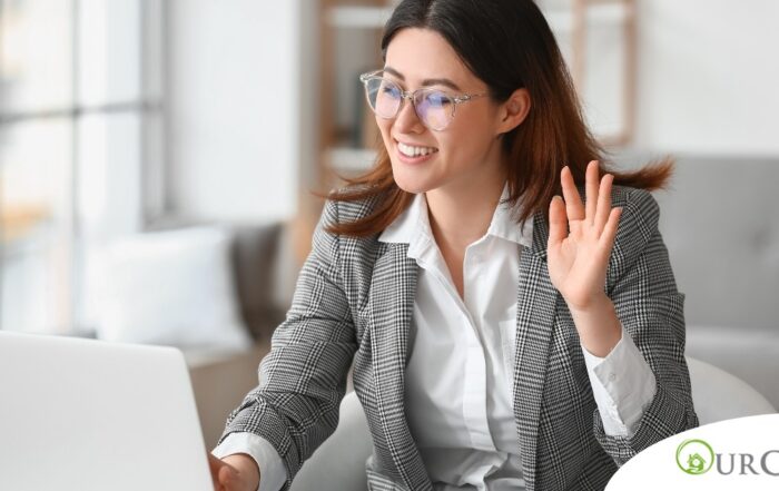 A well-dressed woman smiles and says hi on a videoconference, representing a candidate who is well-prepared for a caregiver interview.