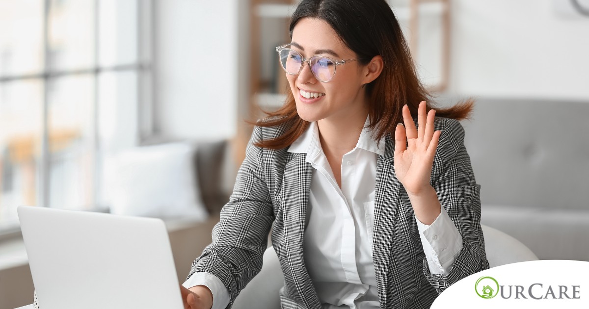A well-dressed woman smiles and says hi on a videoconference, representing a candidate who is well-prepared for a caregiver interview.