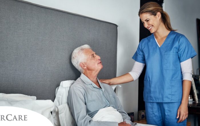 A caregiver smiles at an older client in bed, representing the compassion involved in being a live-in caregiver.