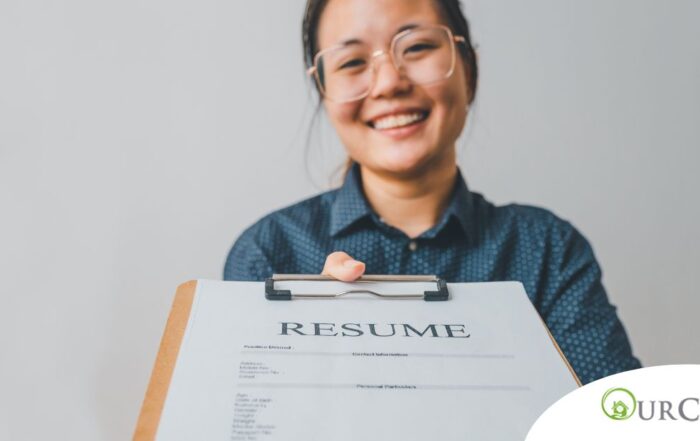 A woman happily hands in a resume, representing a successfully written caregiver resume.