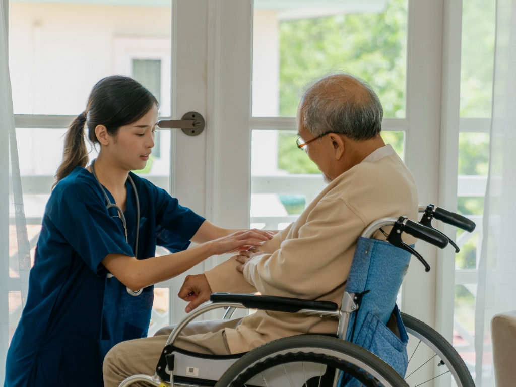 Caregiver providing home care in Tarrytown, New York, assisting a senior man in a wheelchair with compassionate support in a bright, comfortable home setting.