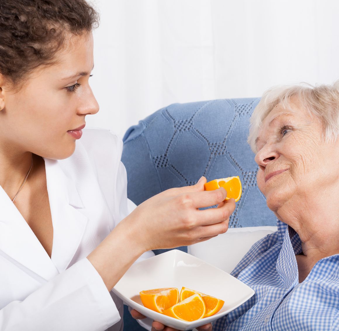A caregiver offering fresh fruit to an elderly woman, providing gentle feeding support and companionship as part of home care in Temple Terrace.